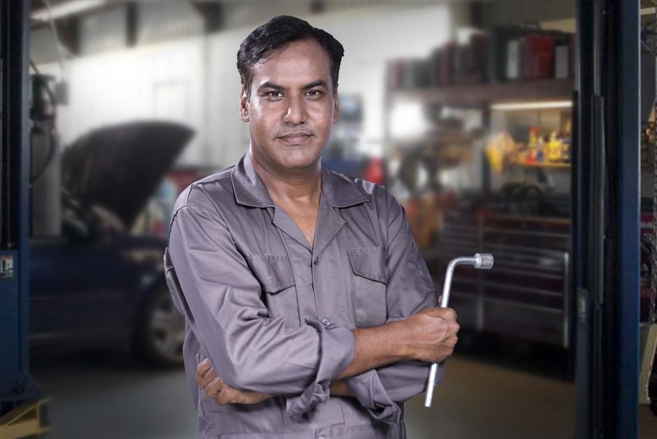 Friendly auto mechanic smiling in a garage